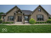Charming brick home featuring a well-manicured lawn, professionally landscaped shrubbery, and a covered front porch at 1740 Golden Field Dr, Greenwood, IN 46143