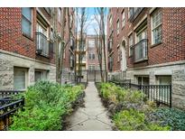 Attractive courtyard view of brick apartment buildings with a landscaped walkway and wrought iron gated entrance at 226 N Cleveland St # 226E, Indianapolis, IN 46204