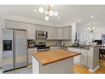 Open kitchen features stainless steel appliances, an island with a butcher block countertop, and gray cabinets at 226 N Cleveland St # 226E, Indianapolis, IN 46204