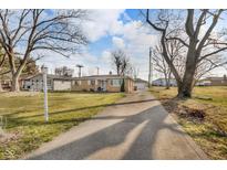 Ranch style home featuring a long driveway and attached garage with mature trees on a large lot at 1731 N Campbell Ave, Indianapolis, IN 46218