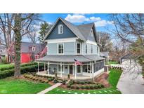 Charming two-story home with a large porch, beautiful landscaping, and lush green grass at 450 W Ash St, Zionsville, IN 46077