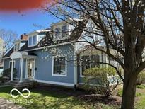Charming blue two-story home with a well-manicured lawn and blooming tree at 590 W Cedar St, Zionsville, IN 46077