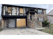 View of severely damaged two-story home with boarded up windows and missing siding, evidence of fire and water damage visible at 6009 Tammin Dr, Indianapolis, IN 46254