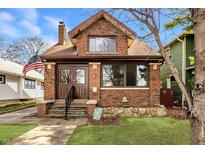 Charming brick home featuring a well-maintained lawn, decorative rock border, and inviting front entrance at 741 Dequincy St, Indianapolis, IN 46201