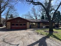 Single story brick home featuring an attached garage, front lawn and mature trees at 8815 Spring Mill Rd, Indianapolis, IN 46260