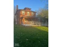 Two-story brick home featuring a wheelchair ramp, covered porch, and mature trees on a lush green lawn at 930 N Ritter Ave, Indianapolis, IN 46219