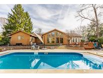 Inviting backyard pool with a spacious patio and charming wood home featuring large windows at 10373 Briar Creek Pl, Carmel, IN 46033
