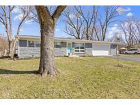 Charming single-story home with stone accents, a light blue door, and a well-manicured front lawn at 10427 N Delaware St, Carmel, IN 46280