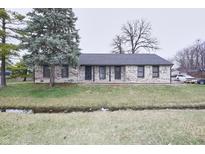 Ranch-style house featuring a brick facade, black trim, well-manicured lawn, and mature trees, exuding classic charm at 1164 Prairie Depot, Indianapolis, IN 46241