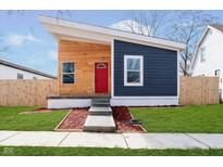 Modern home featuring a unique angular roof, wood and navy siding, and a bright red front door at 242 N Tacoma Ave, Indianapolis, IN 46201