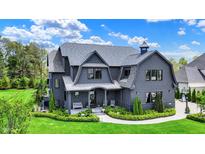 Stunning two-story home showcasing professional landscaping, a well-manicured lawn, and a welcoming front porch with seating at 5120 Melbourne Pl, Zionsville, IN 46077