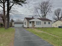 Charming single-story home with detached garage and ample driveway space on a cloudy day at 125 Ursal Ln, Greenwood, IN 46143