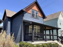 Charming two-story home with blue siding, an orange gable, black trim, and a covered front porch with modern railing at 1334 E Market St, Indianapolis, IN 46202