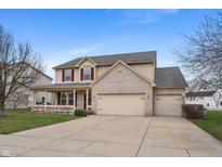 Inviting two-story home with a brick-accented facade, attached three-car garage, and a charming covered porch at 1975 Westminster Pl, Columbus, IN 47201