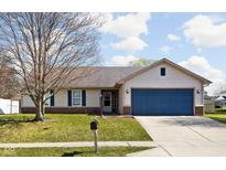 Charming single-story home featuring blue garage door, tidy landscaping and brick accents at 353 Brixton Woods W Dr, Pittsboro, IN 46167