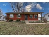 Inviting single-story brick home featuring a cozy covered front porch, green shutters and landscaped garden at 4812 Eastgate Dr, Columbus, IN 47203