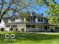 Stunning two-story home featuring a welcoming wrap-around porch, a well-manicured lawn, and mature shade trees at 7984 S Deer Lake Dr, Nineveh, IN 46164