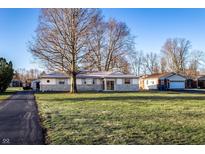 Ranch-style home with stone accents, well-maintained lawn, mature trees, and classic charm on a sunny day at 9619 E Southport Rd, Indianapolis, IN 46259