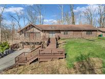 A multi-level brick house showcasing a wooden deck and stairs in a large yard with trees in early spring at 108 Parkridge Dr, Danville, IN 46122