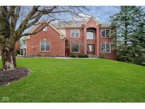 Stunning two-story red brick home with a lush green lawn and mature trees enhancing curb appeal at 11733 Creekstone Way, Zionsville, IN 46077