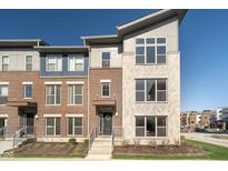 Modern townhouse with brick and gray stone facade, complemented by well-maintained landscaping and ample natural light at 12938 Grand Vue Dr, Carmel, IN 46032