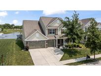 A charming two-story home features a well-manicured lawn, pond and an attached two-car garage at 12959 Balfour Rd, Fishers, IN 46037