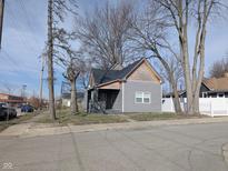 Charming home featuring gray vinyl siding, a covered porch, and mature trees, offering great curb appeal at 1546 S New Jersey St, Indianapolis, IN 46225