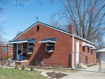 Charming brick home featuring a well-maintained lawn, complemented by blue awnings and a walkway to the entrance at 311 S Webster Ave, Indianapolis, IN 46219