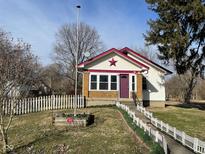 Charming home featuring a well-maintained yard and eye-catching purple door and maroon trim at 7332 Dobson St, Indianapolis, IN 46268