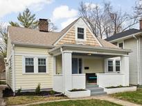 Charming single-story home featuring a covered front porch, light yellow siding and a landscaped front yard at 5252 N College Ave, Indianapolis, IN 46220