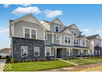New townhouses showcasing brick and siding exteriors, complemented by well-maintained front lawns and blue skies at 5771 Cr W 750 N, McCordsville, IN 46055