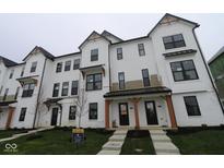 Modern townhome featuring a white brick and board and batten exterior, dark trim, covered porch, and manicured lawn at 7081 Pate Hollow Dr, Brownsburg, IN 46112