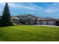 Spacious brick home with a three-car garage, lush green lawn, and basketball hoop in a suburban setting at 9398 W Mirror Rd, Columbus, IN 47201