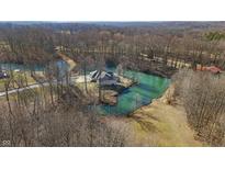 Idyllic aerial view of a stone home surrounded by tranquil water and mature trees in a peaceful, secluded setting at 2437 W Wavelyn N Cir, Martinsville, IN 46151