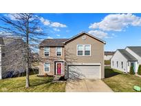 Charming two-story home with a well-maintained lawn, a garage and a pink front door with wreath at 8110 Crackling Ln, Indianapolis, IN 46259