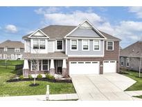 Inviting two-story home featuring a three-car garage, a brick and siding facade, and a well-manicured lawn at 18203 Sunbrook Way, Westfield, IN 46074