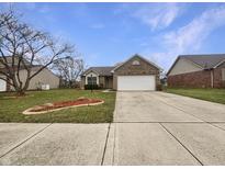 Charming brick home featuring a well-manicured front yard and a two-car garage on a sunny day at 1310 Scarlett Dr, Anderson, IN 46013