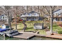 Lakefront home boasts multiple decks, a lakeside dock, and mature trees surrounding manicured lawn at 6290 Grouse Dr, Nineveh, IN 46164