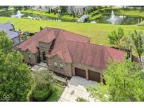 Stunning aerial view of the brick home, manicured lawn, pond, and three car garage at 6823 Abercon Trl, Noblesville, IN 46062