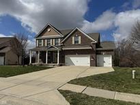 Charming two-story brick home with a three-car garage, landscaped yard, and inviting front porch at 8474 Dumfries Dr, Brownsburg, IN 46112