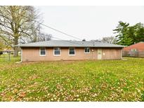 Back exterior view of home with brick siding, three windows and a manicured lawn covered with fall leaves at 2543 Thayer Ct, Anderson, IN 46011