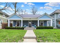 Charming blue home featuring a cozy front porch, well-manicured lawn, and inviting curb appeal at 3535 Birchwood Ave, Indianapolis, IN 46205