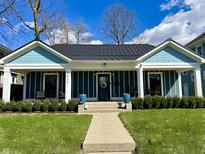 Charming curb appeal with a blue exterior, black roof, landscaped lawn, and inviting front porch at 3535 Birchwood Ave, Indianapolis, IN 46205