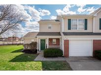 Charming townhome with a well-maintained lawn, attached garage, and inviting front porch with green door at 1568 Brookfield Cir, Franklin, IN 46131