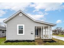 Charming gray home featuring a covered porch and well-maintained landscaping at 209 Pennsylvania St, Shirley, IN 47384