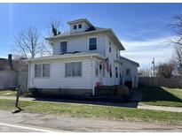 Charming two-story home with a traditional design and an American flag waving on the porch at 238 S Main St, Wilkinson, IN 46186
