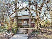 Two story home with trees framing the entrance stairs, and a covered front porch at 2505 E 17Th St, Indianapolis, IN 46218