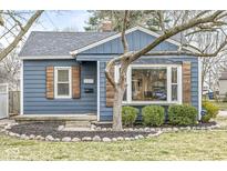 Charming blue home featuring a tidy front yard with a rock border and lush greenery at 5377 Evanston Ave, Indianapolis, IN 46220