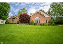 Charming brick home featuring manicured landscaping and a lush green lawn at 7732 Ashtree Dr, Indianapolis, IN 46259