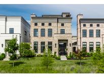 Attractive townhome with brick facade, black framed windows, well manicured lawn, and neatly landscaped flowerbeds at 12099 Sigillary Way, Carmel, IN 46032